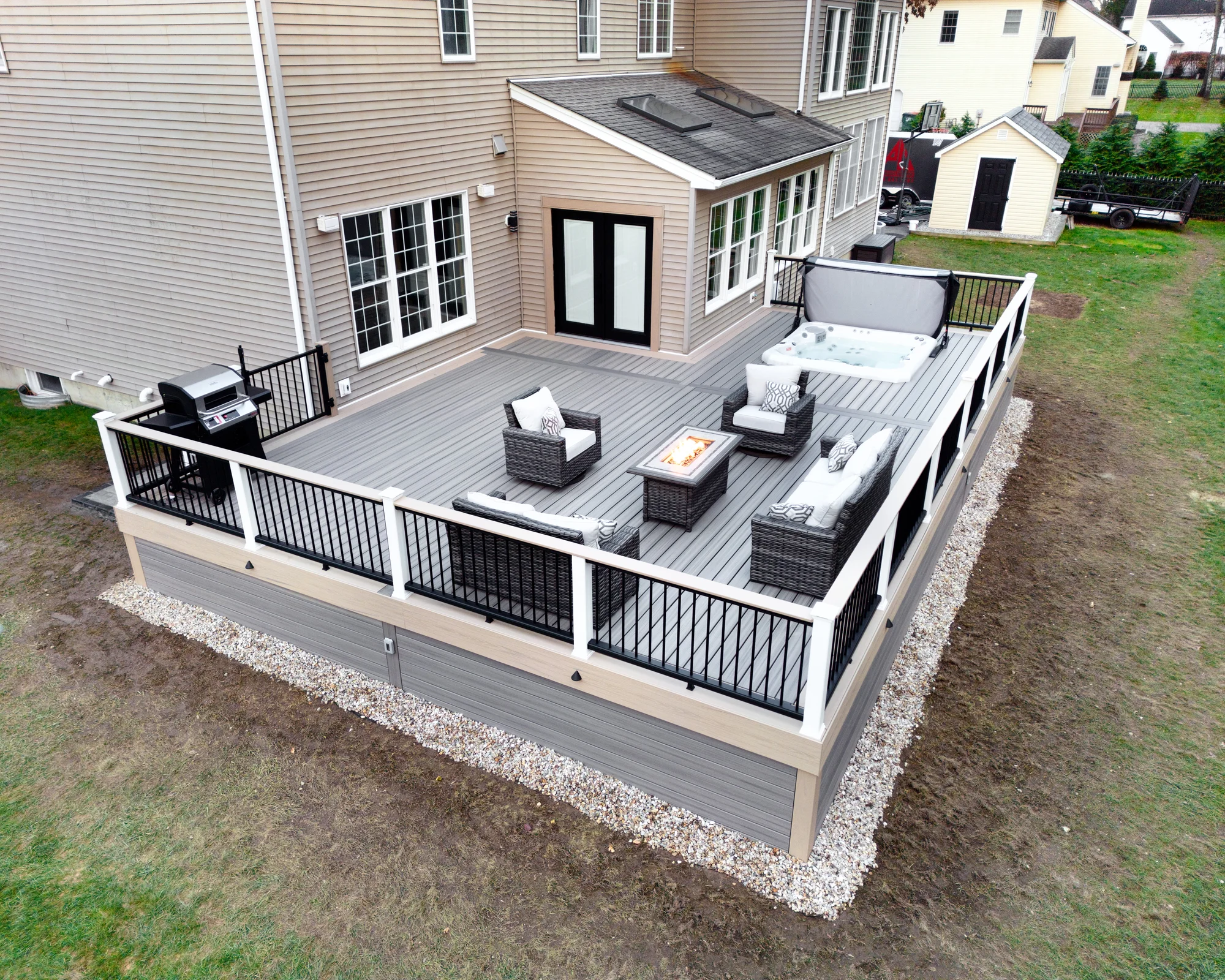 Fire pit and hot tub on an elevated Trex deck lit at night